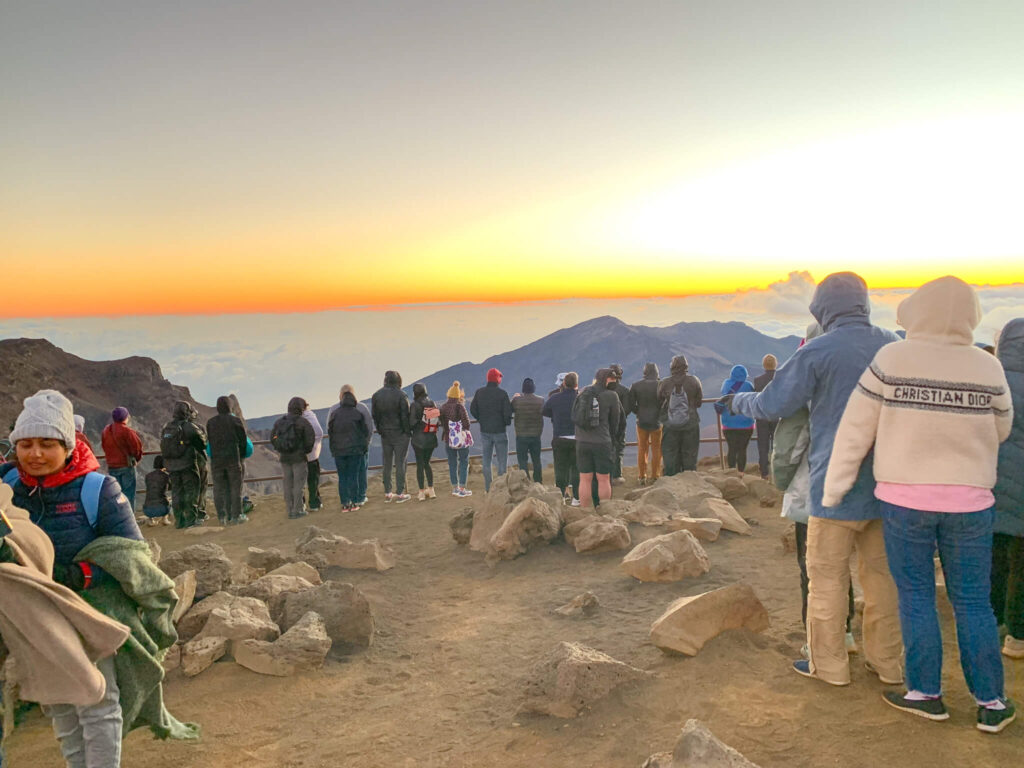 Image of people lined up at the railing to see the Maui sunrise at Haleakala National Park.