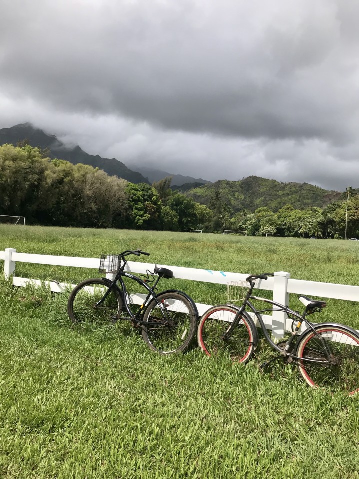 Image of two bikes leaning up against a white fence near a soccer field on Kauai.