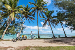 Find out the best Kauai bike trails recommended by top Hawaii blog Hawaii Travel with Kids. Image of a family biking on a beach in Hawaii