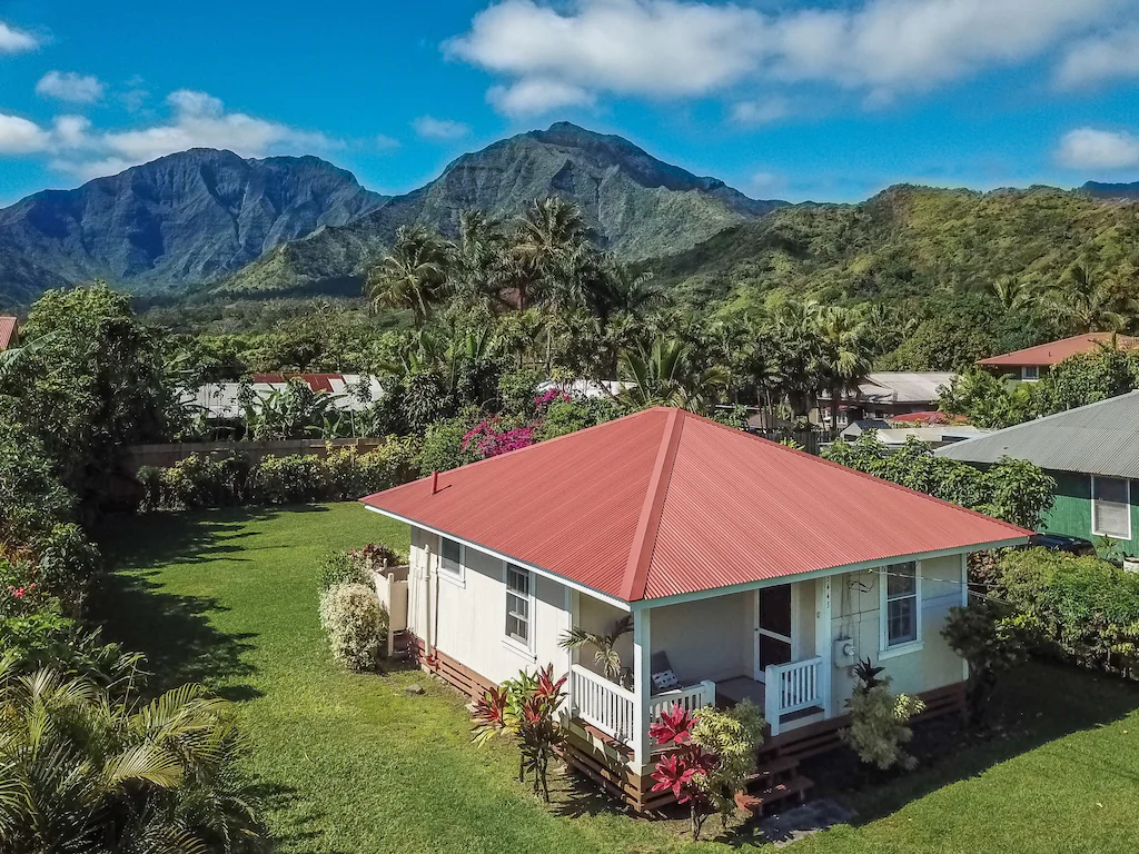 Image of a white North Shore Kauai vacation rental home with lush mountains in the background