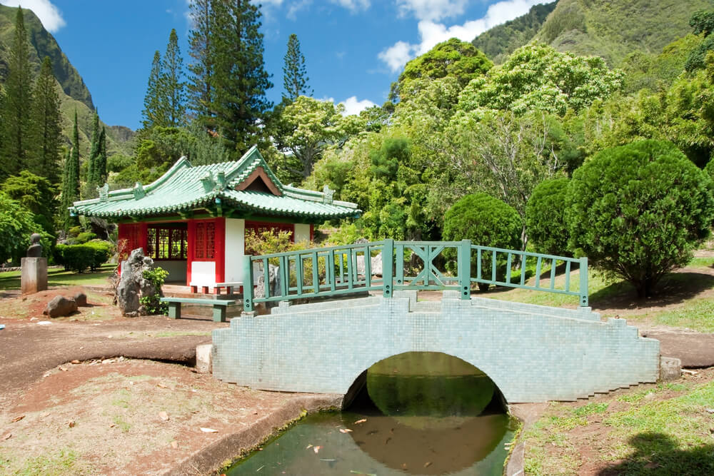 Image of a bridge over a stream and a red temple in Iao Valley on Maui.