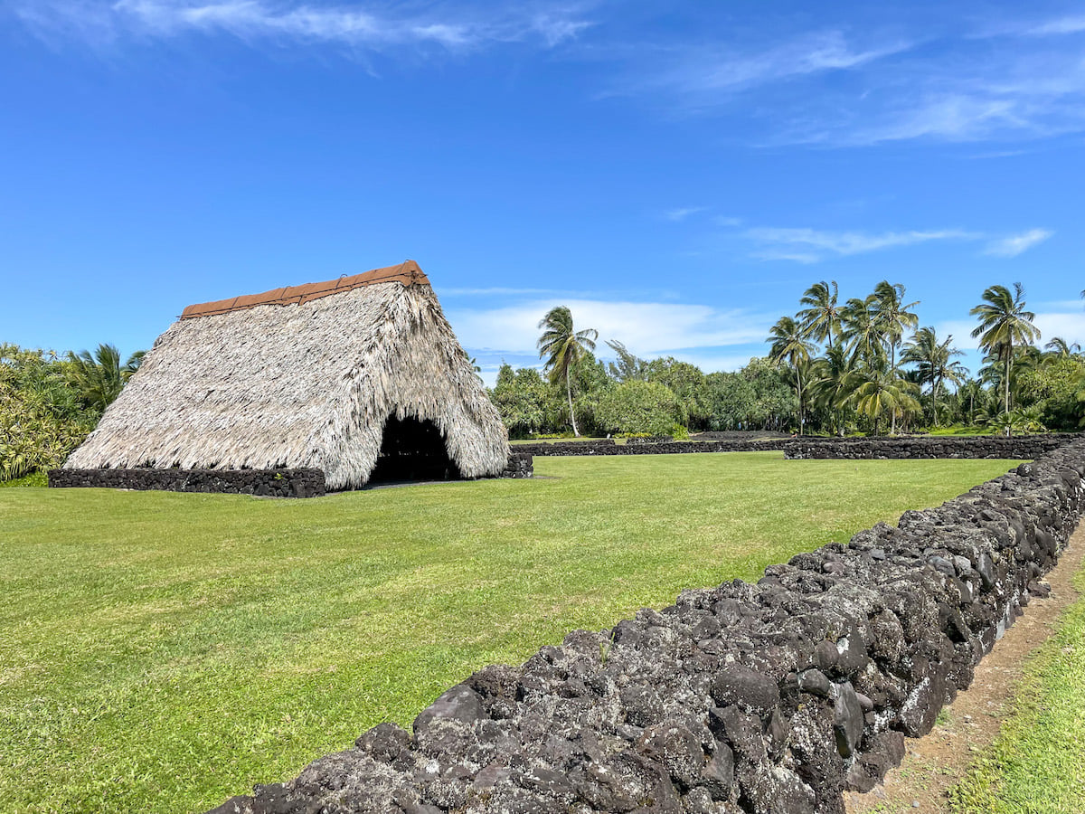 Check out this guide to Kahanu Garden in Hana Maui by top Hawaii blog Hawaii Travel with Kids. Image of a Hawaiian hut and lava rock wall at a Maui botanical garden