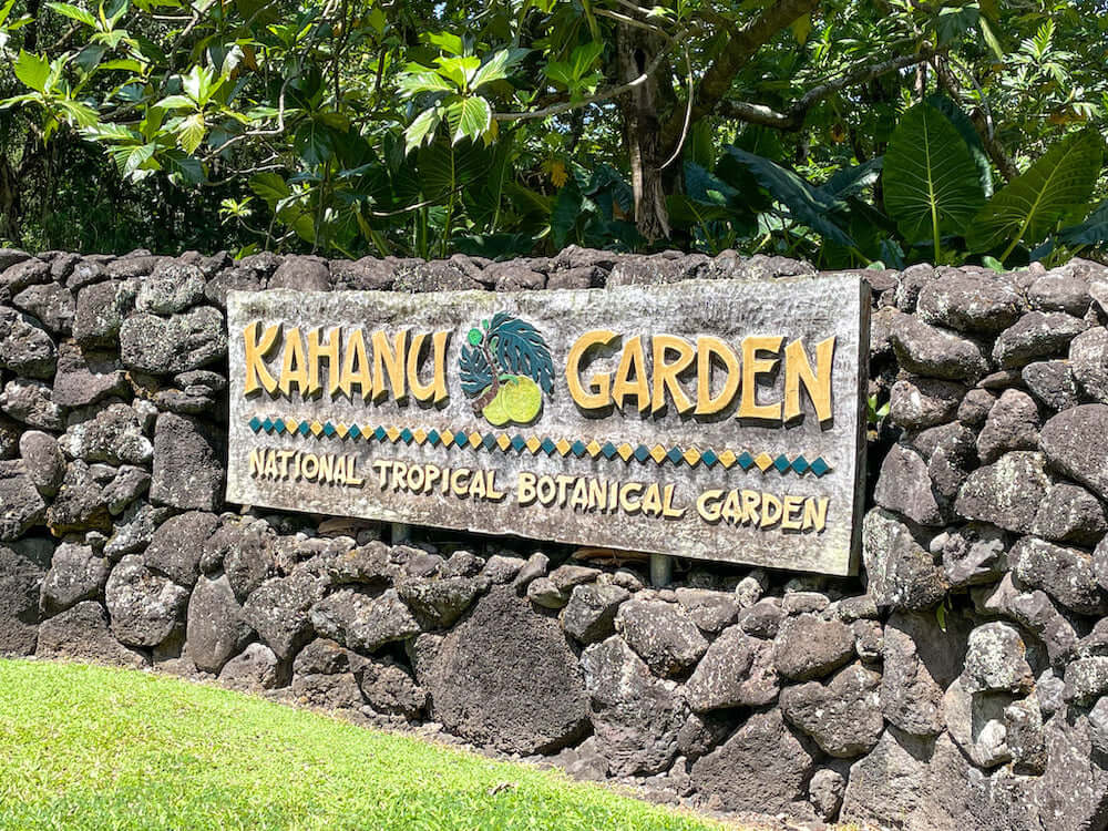 Image of the Kahana Garden sign on a lava rock wall in Maui.