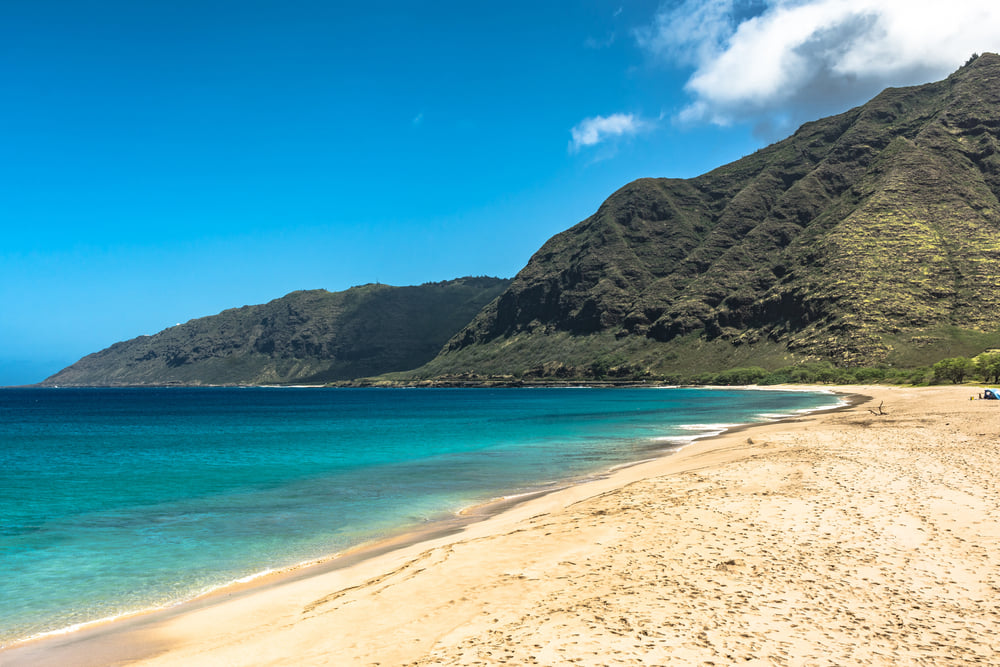 Image of a secluded beach on Oahu with mountains in the background.