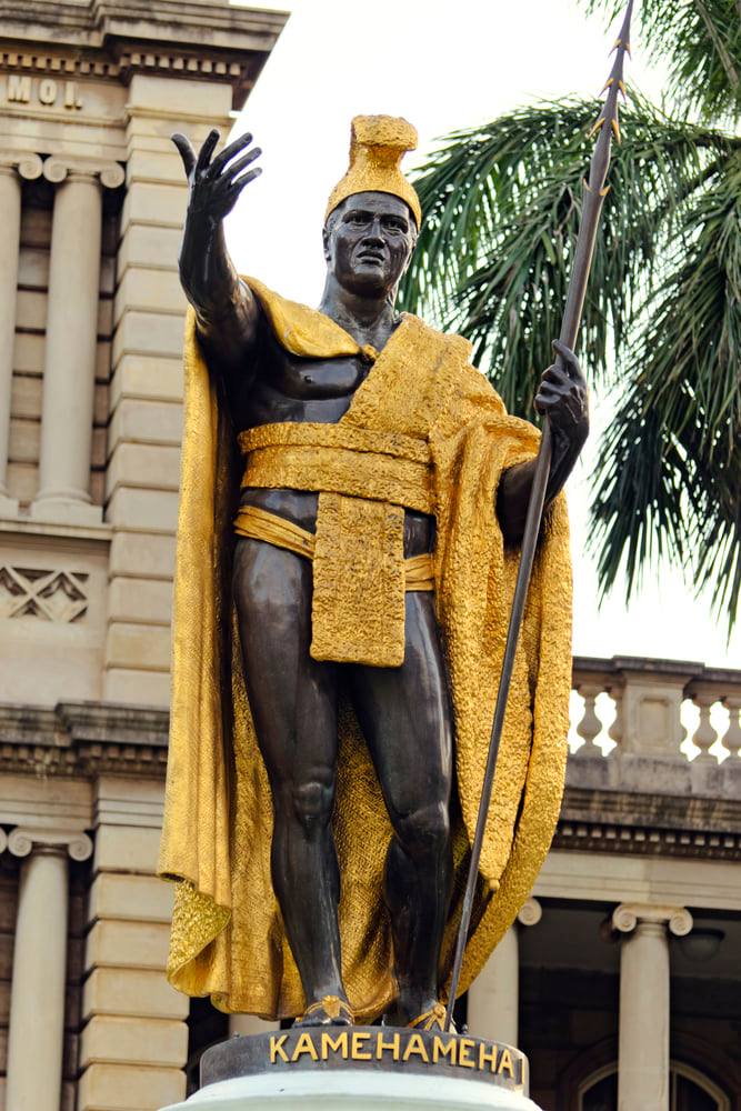 Image of a statue of a Hawaiian king with gold clothing outside of Iolani Palace on Oahu.