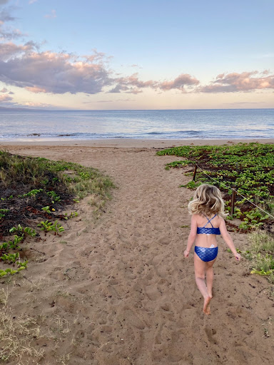 Image of a girl wearing a blue swimsuit running on the beach