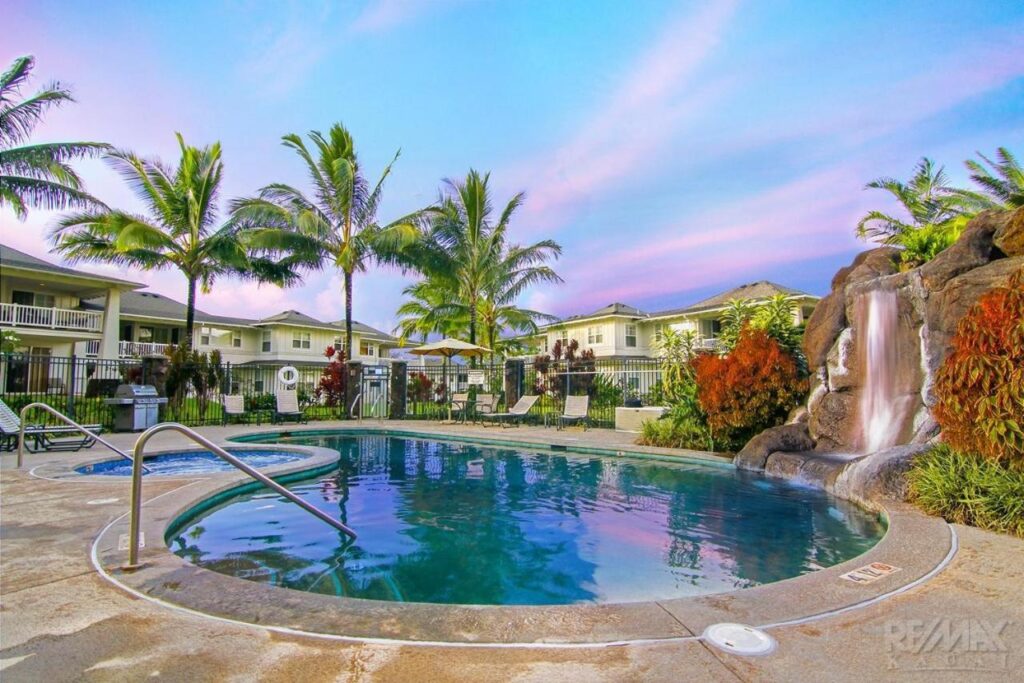 Image of a swimming pool with little waterfall surrounded by condos in North Shore Kauai.