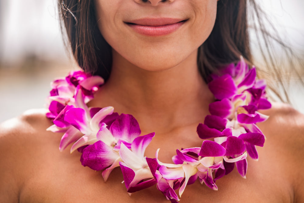 Image of a woman wearing a short purple orchid lei.