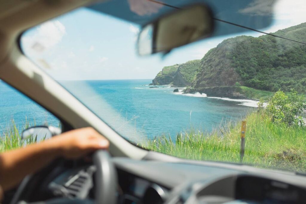 Check out the best Road to Hana tours recommended by top Hawaii blog Hawaii Travel with Kids. Image of someone driving the Road to Hana on Maui