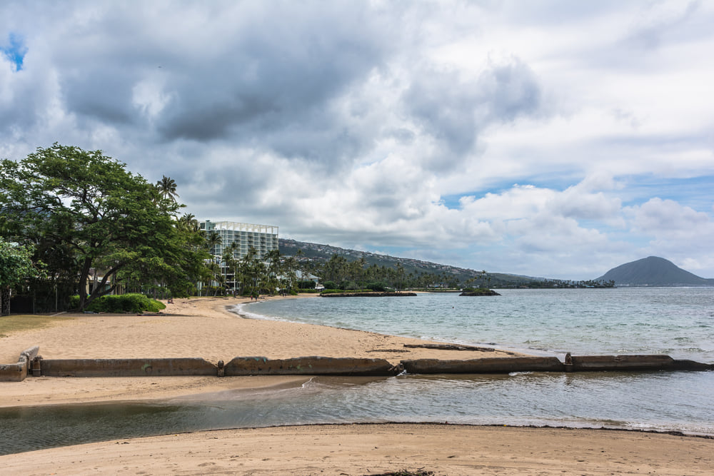 Image of a sandy beach with calm water and a view of Koko Head in the background.