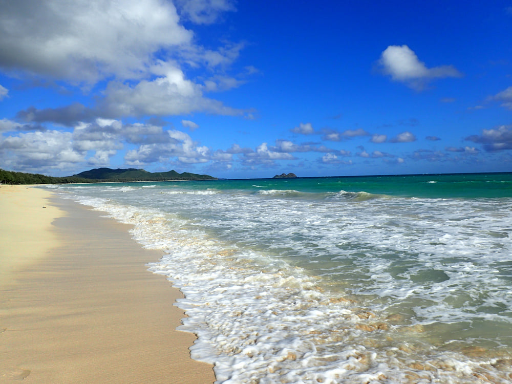 Image of a golden sandy beach with little mountains in the background.