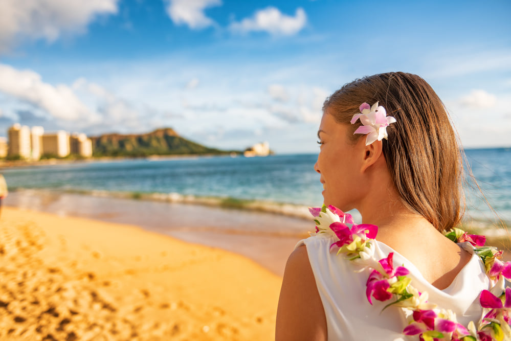 Image of a woman wearing a colorful lei on Waikiki Beach with Diamond Head in the background