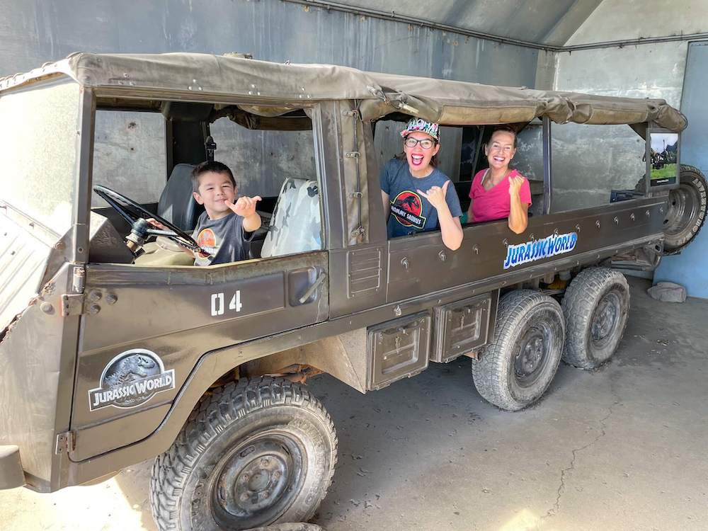 Image of a grandma, mom, and son inside the Jurassic World truck.