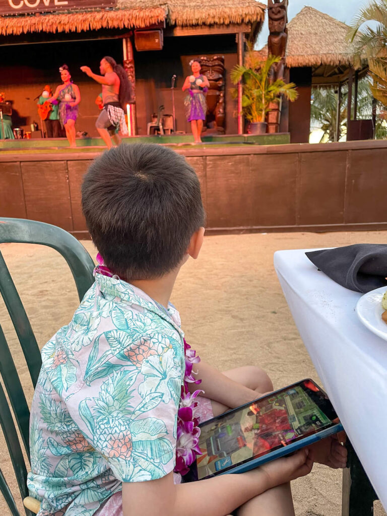 Image of a boy holding an iPad at the Paradise Cove luau on Oahu.