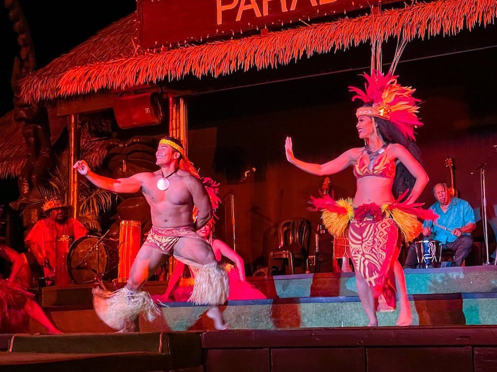 Image of a man and woman dressed in Tahitian traditional clothing dancing on stage at the Paradise Cove Luau on Oahu.