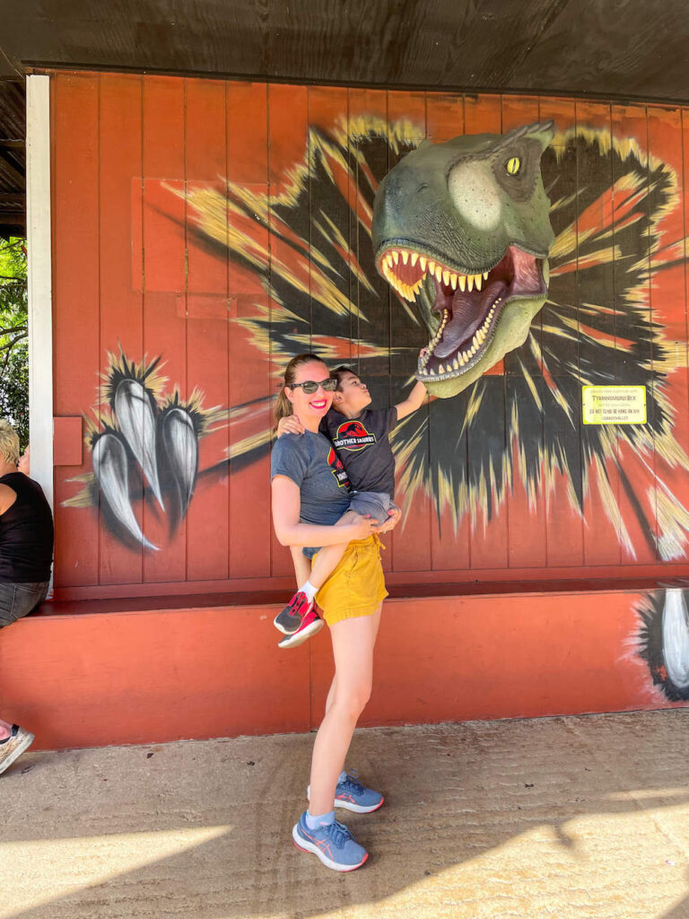 Image of a mom and son next to a T-Rex head popping out of a wall at Kualoa Ranch on Oahu