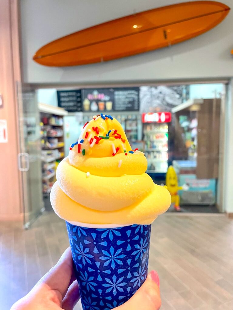 Image of a cup of Dole Whip with sprinkles in front of the Aloha Whip shop in Waikiki