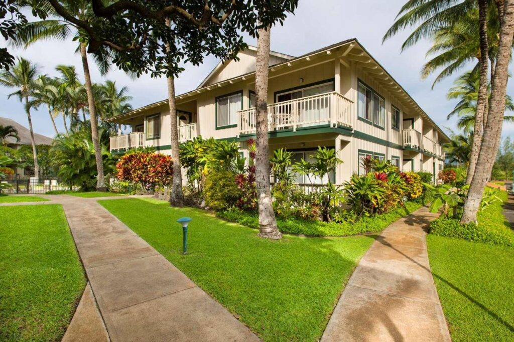 Image of a two story building with palm trees around it and two paths