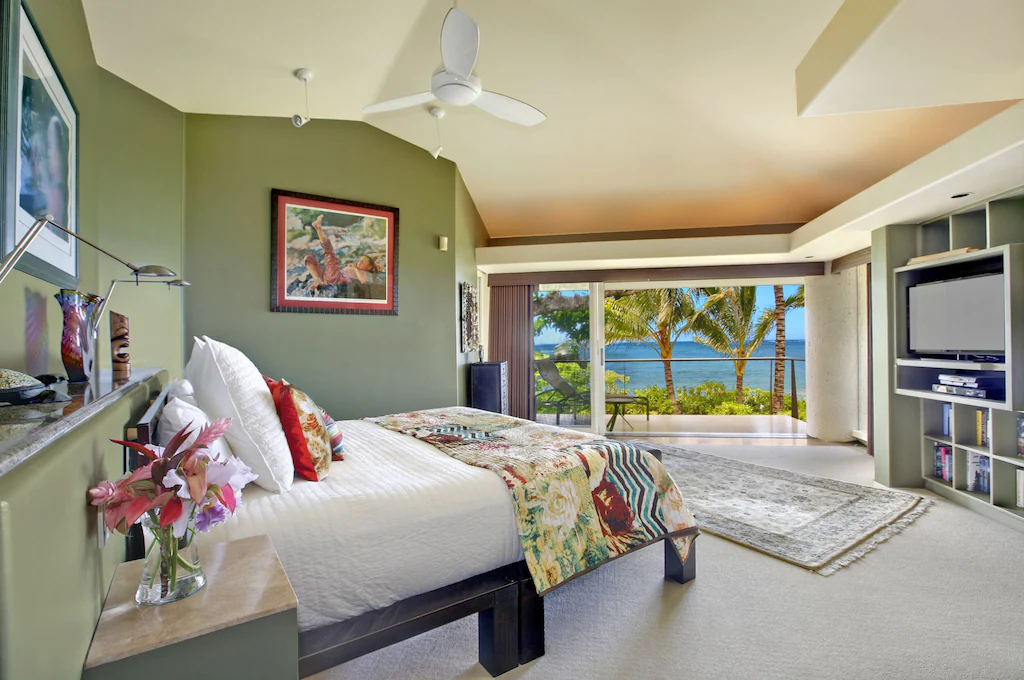 Image of a bedroom with open sliding doors overlooking an ocean view with palm trees