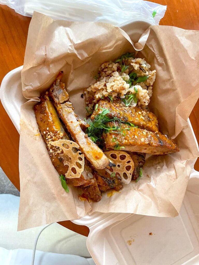 Image of a takeout box with lilikoi ribs and garlic fried rice.