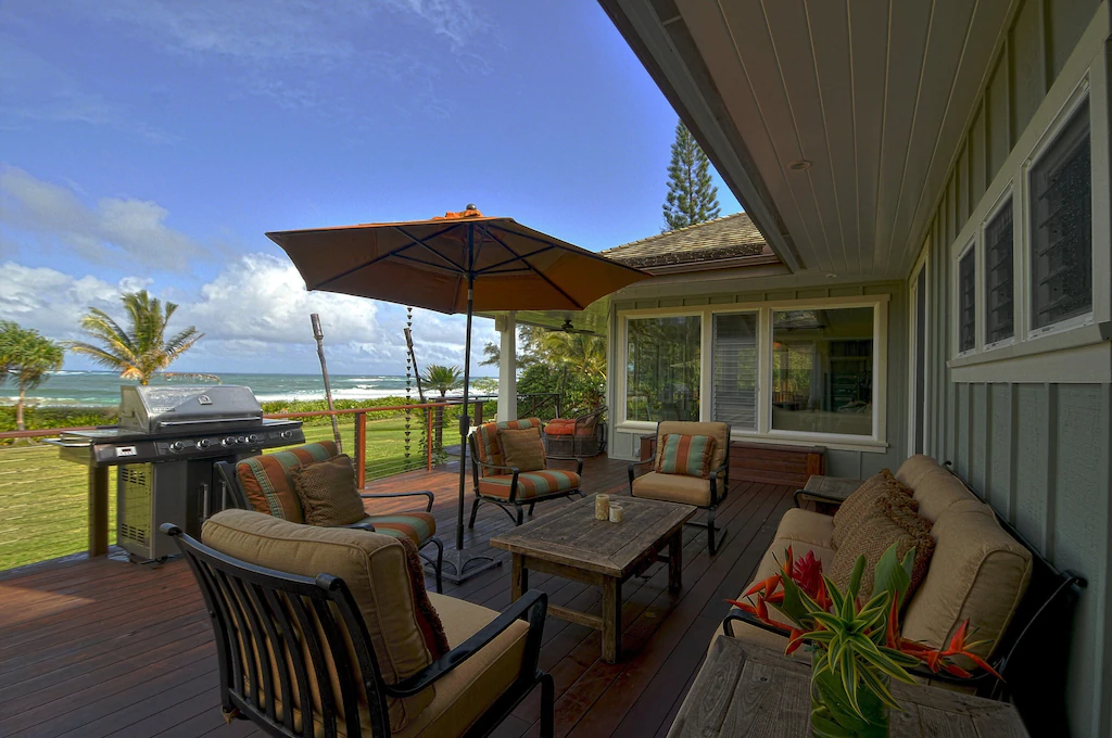 Image of an outdoor patio set and grill on a deck next to a KAuai beach