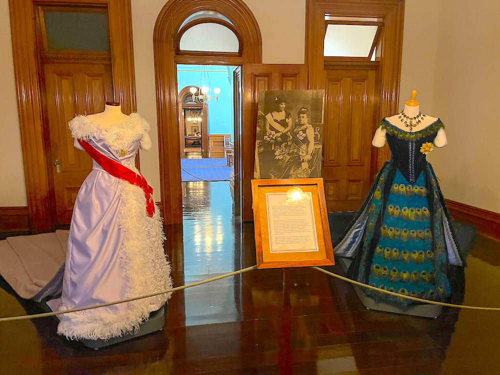 Image of a white feather ballgown and a peacock feather ballgown at Iolani Palace in Honolulu.