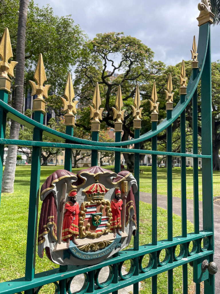 Image of the Hawaiian royal emblem on a green gate outside of Iolani Palace in Hawaii.