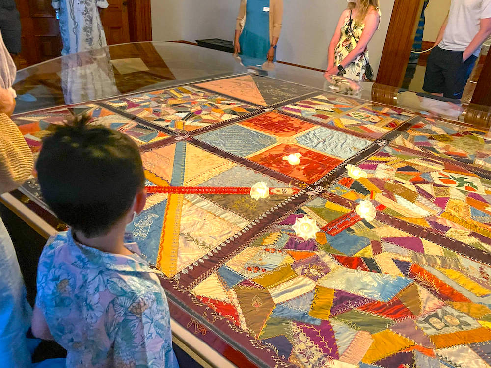 Image of a boy looking at a patchwork quilt that is in a glass case.