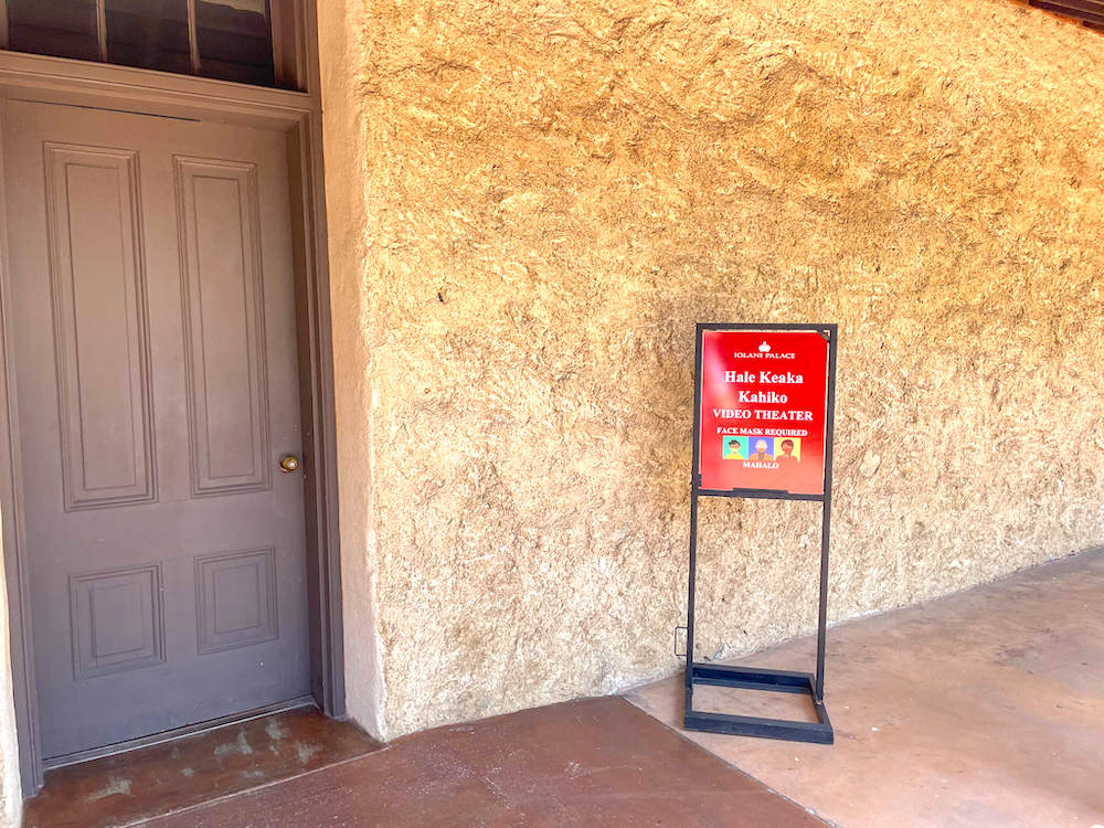 Image of a sign and brown door at Iolani Palace.