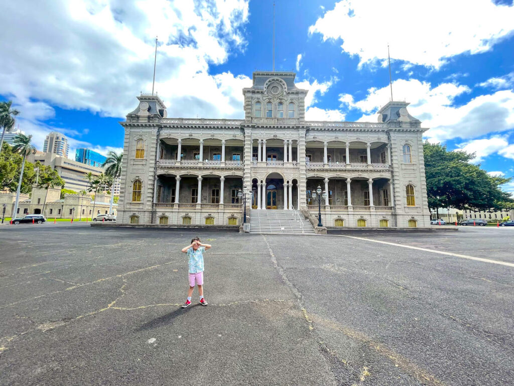 Image of a boy standing in front of Iolani Palace in Honolulu Hawaii.