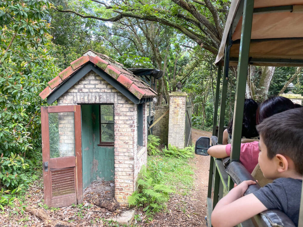 Image of a boy with his arm out of the window looking at a replica guard house