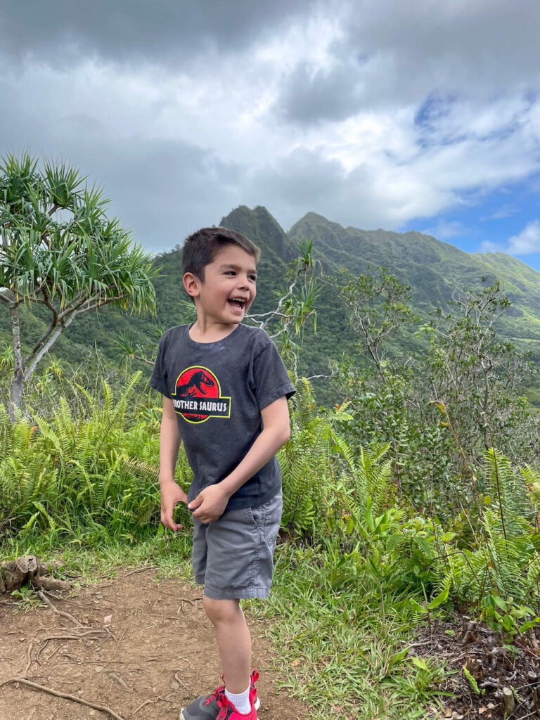 Image of a boy laughing in front of tropical mountains on Oahu