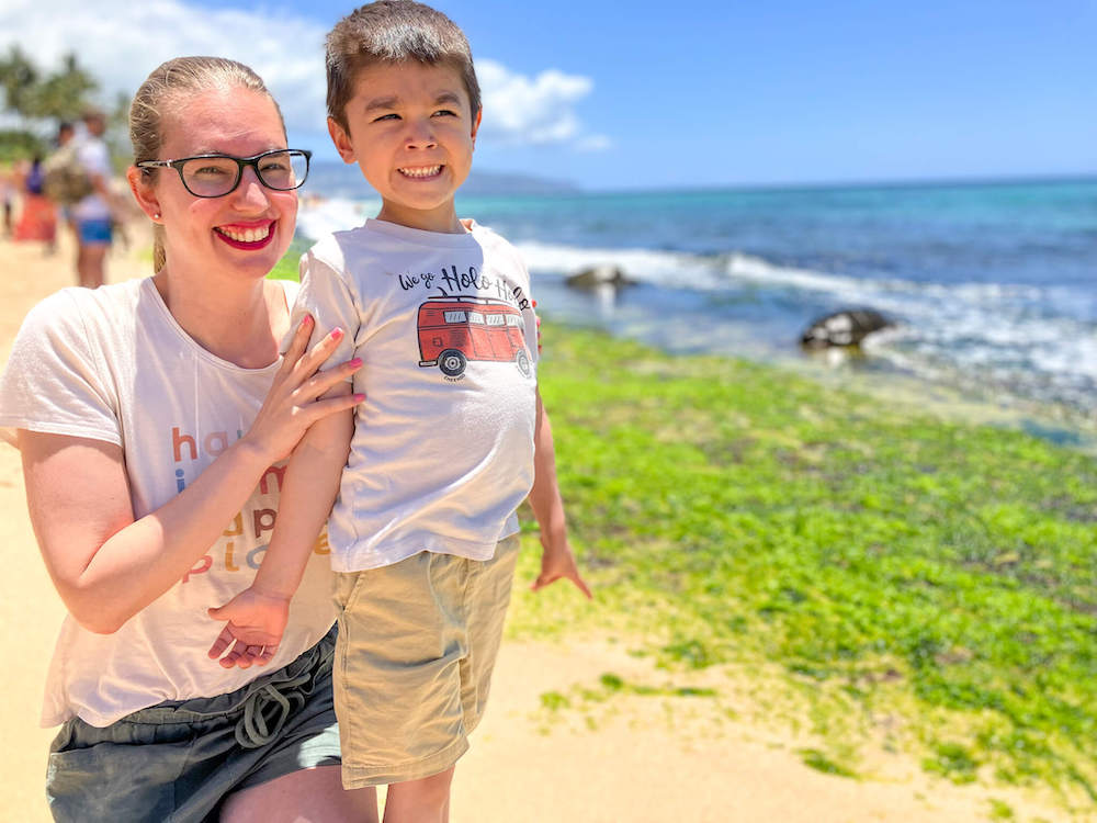 Image of a mom and son smiling at Laniakea Beach with sea turtles in the background