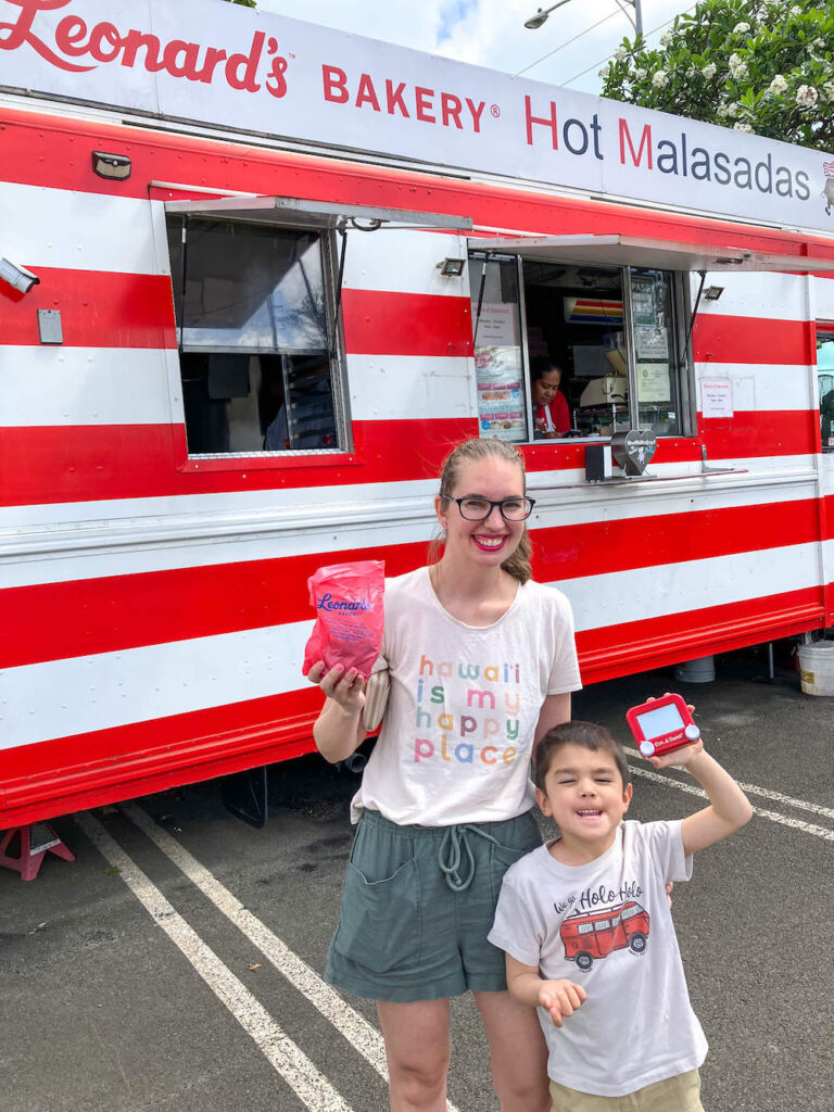 Image of a mom and son posing in front of a red and white striped food truck on Oahu