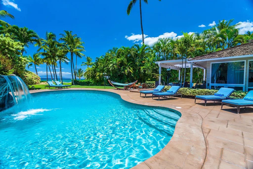 Image of a pool with a waterfall and several beach lounge chairs