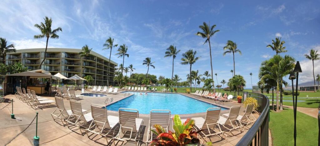 Image of a large pool surrounded by white lounge chairs