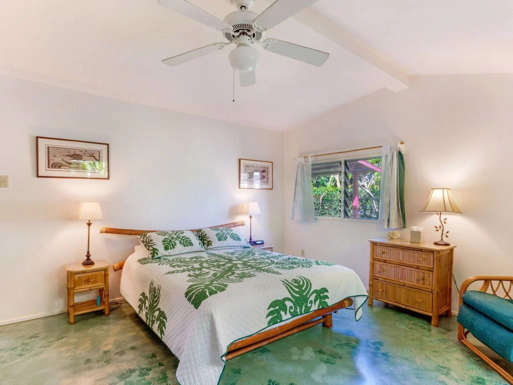 Image of a bedroom with a green and white Hawaiian quilt on the bed