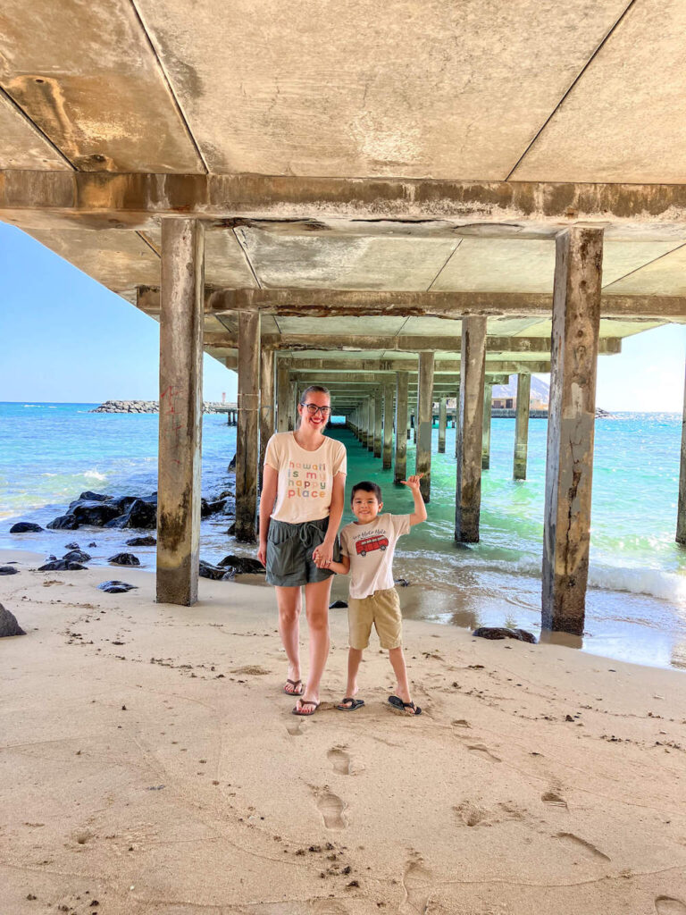 Image of a mom and son standing underneath a pier on Oahu