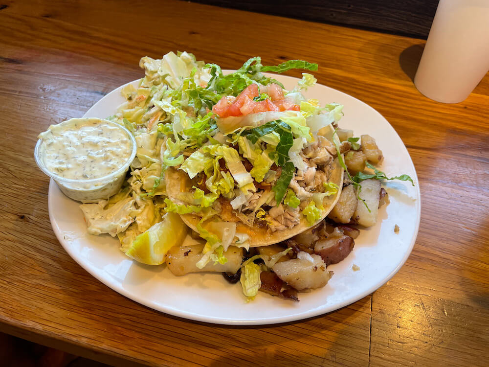 Image of a plate of fish tacos, salad, and home fries.