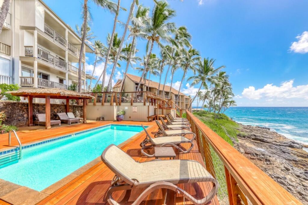 Image of a skinny pool and deck chairs facing the ocean