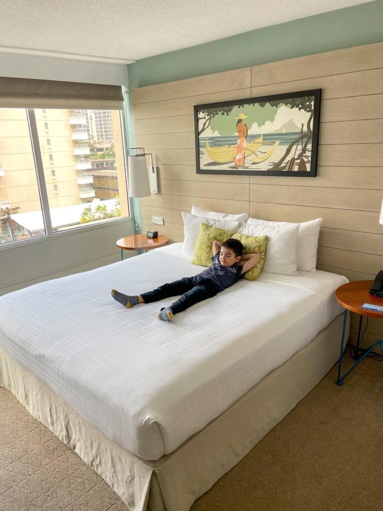 Image of a boy relaxing on a freshly made bed at a Waikiki hotel.