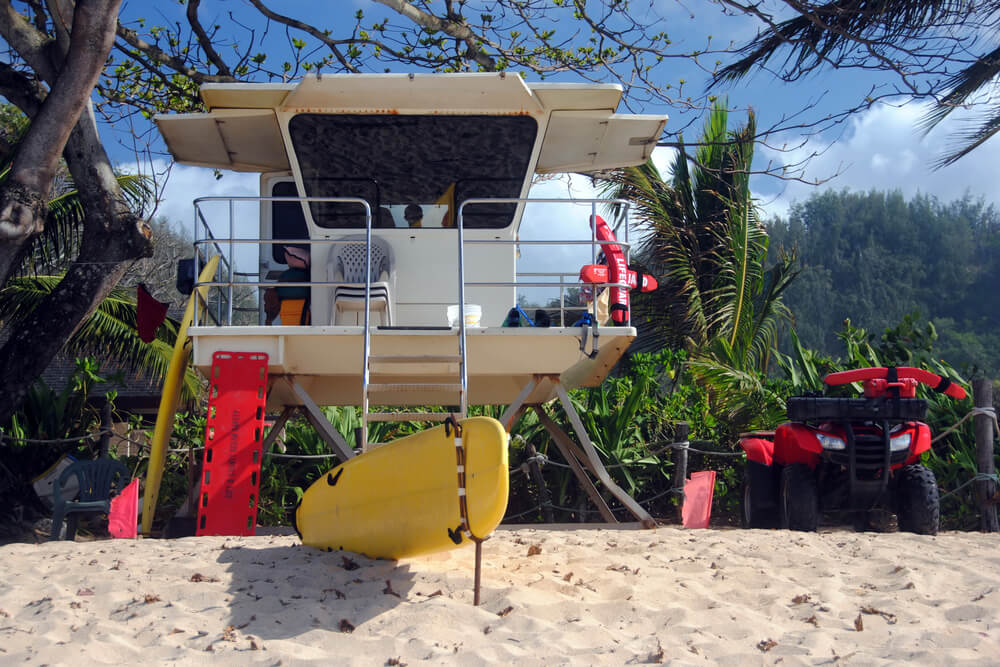 Image of a lifeguard station, red ATV, and a yellow surfboard at a North Shore Oahu beach