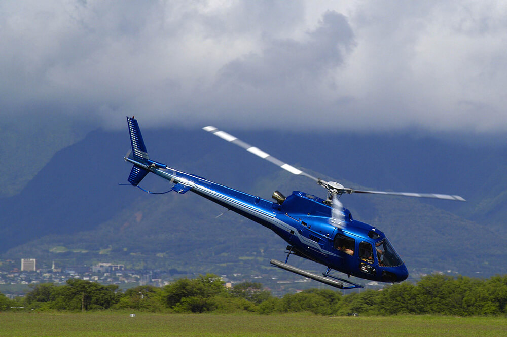 Image of a blue helicopter landing at Kahului Airport on Maui