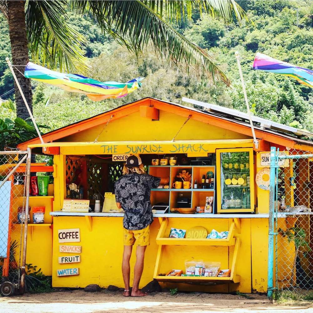 Image of a man ordering at the Sunrise Shack, a yellow roadside stand with fresh fruit and coffee
