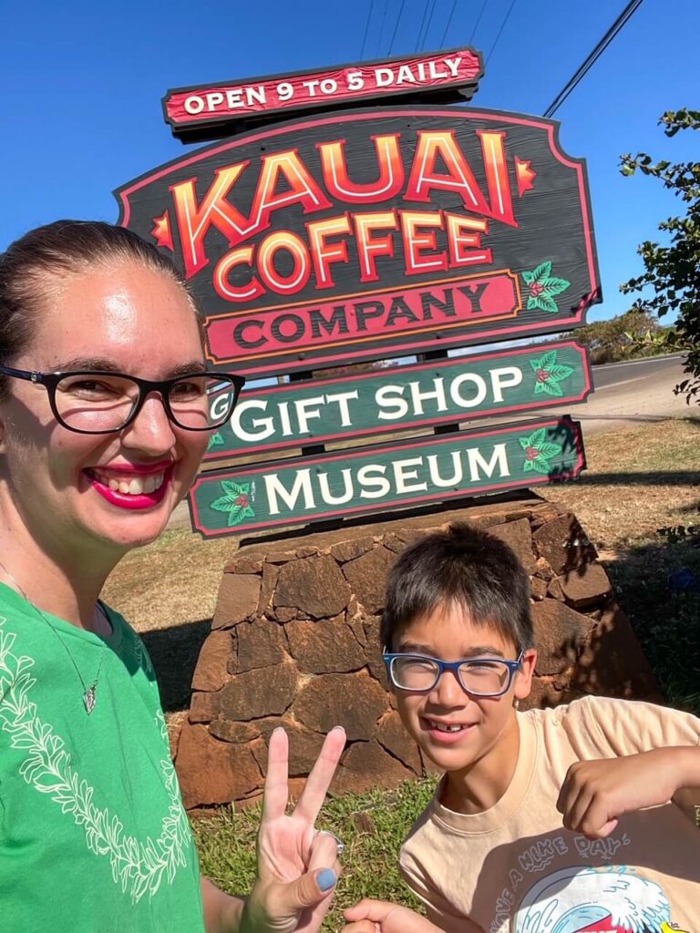 Kauai Coffee Farm Tour: Image of a mom and boy taking a selfie in front of the KAuai Coffee Company sign