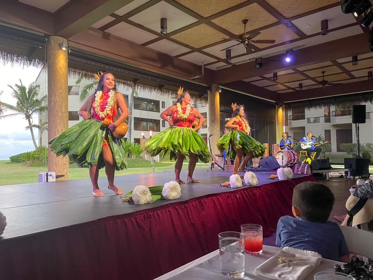 Check out this Luau Ka Hikina review by top Hawaii blog Hawaii Travel with Kids! Image of a boy watching hula dancers at a Kauai luau