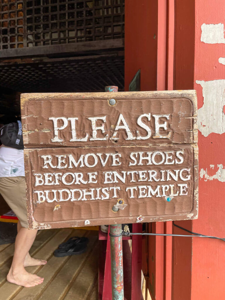 Please remove your shoes before entering the Byodo-In Temple on Oahu. Image of a sign saying please remove shoes before entering Buddhist temple.
