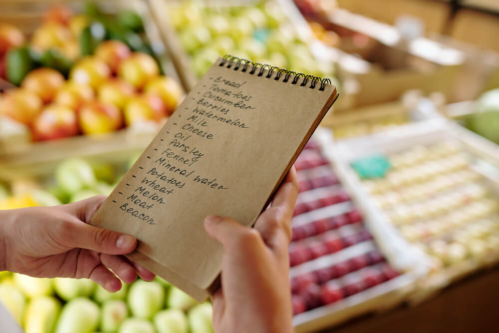 Image of a brown shopping list with fruit in the background