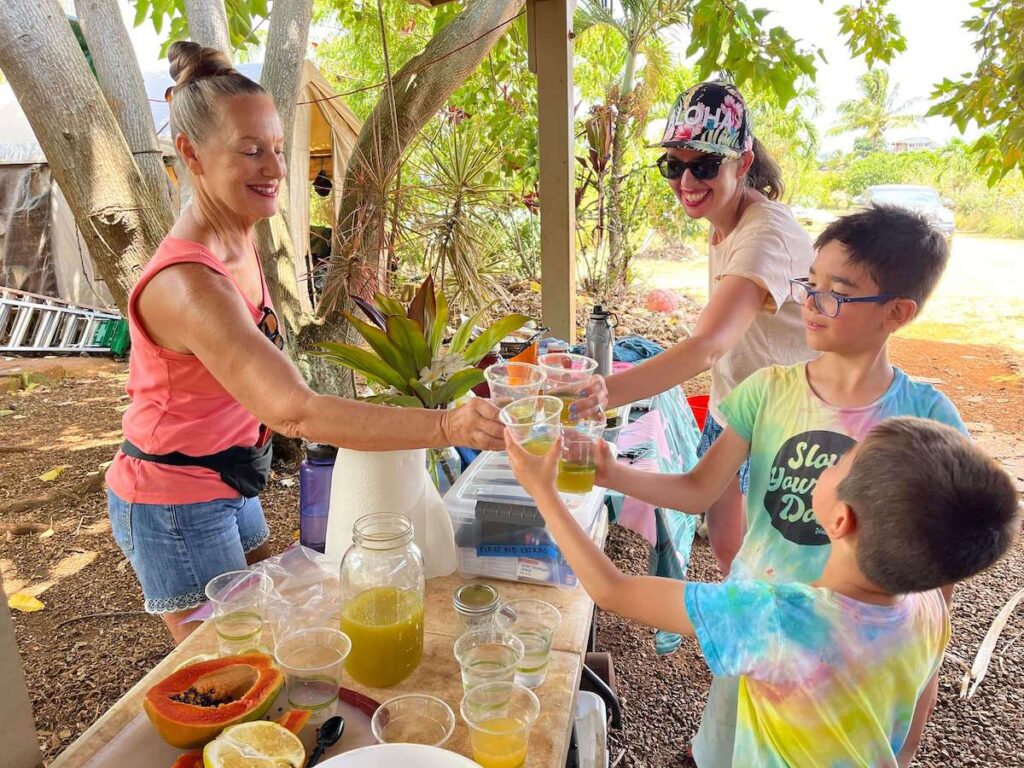 Image of a grandma, mom, and two boys doing cheers with cups of freshly squeezed sugar cane juice