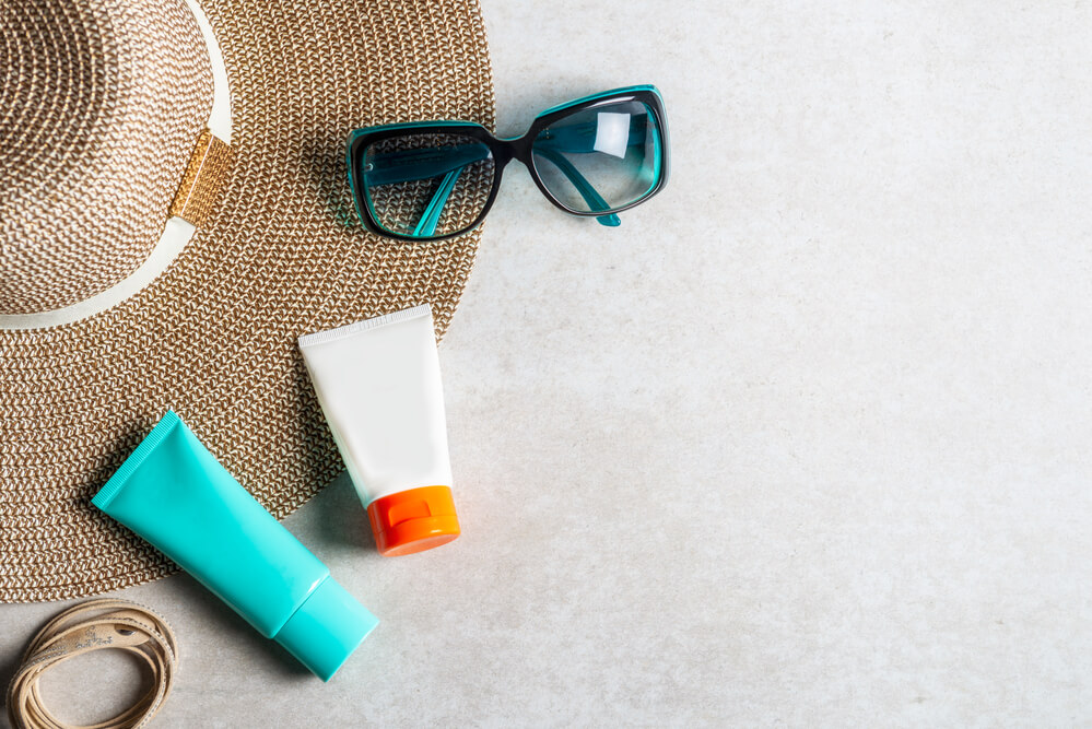Image of a straw hat, sunglasses, and sunscreen